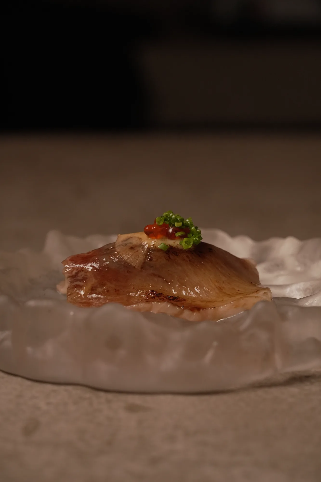 Torch-seared fish with garnish served over ice at Shun Omakase Counter, Canggu
