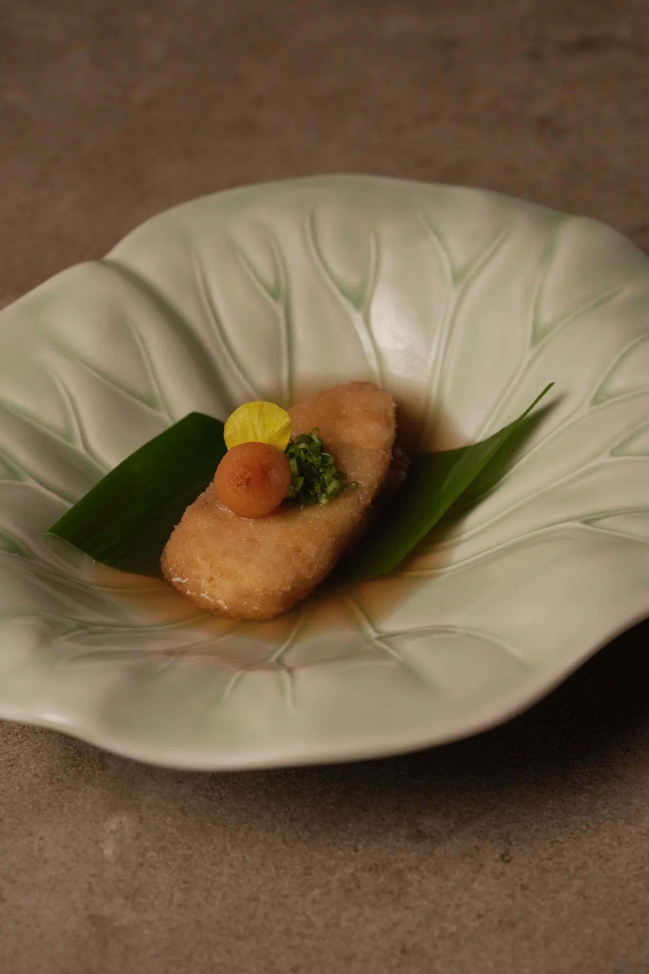 A plated omakase course on a leaf-lined dish at Shun Omakase Counter, Canggu